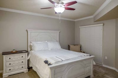 Cozy private bedroom with a white bed and fan