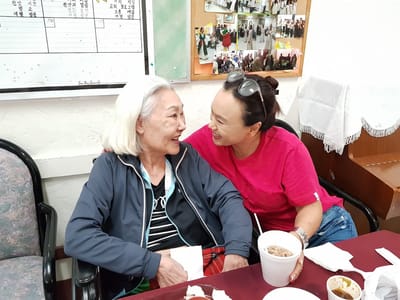 Two women enjoying a joyful moment together in a communal space.
