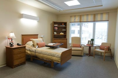Interior view of a private resident room with a bed and chair
