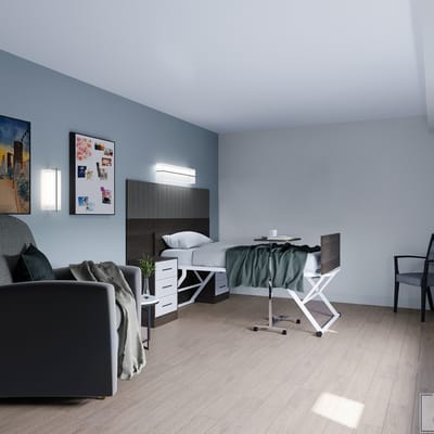A neatly arranged private resident room with bed and seating area