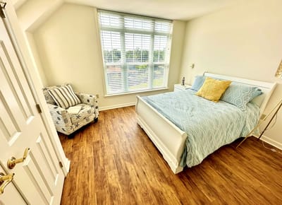 A well-decorated resident room with a bed and chair