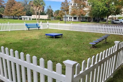 Outdoor fenced area with benches and grass