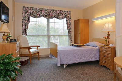 A cozy resident room with floral curtains and a hospital bed