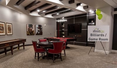 A billiards room with a pool table and seating area