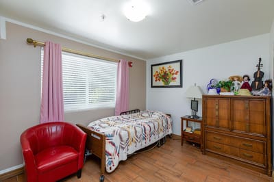 A cozy resident room with a bed and armchair