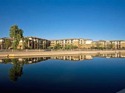 Exterior view of La Siena facility across a reflective water body