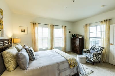 A well-furnished resident room with a bed and window