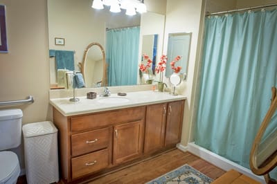 Bright and clean bathroom with wooden vanity and floral decor