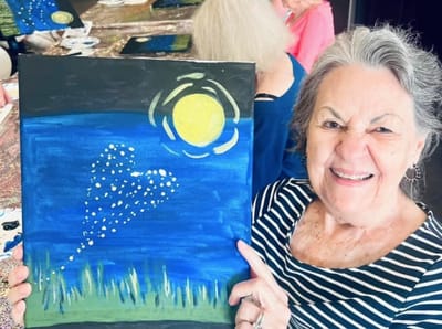 Resident showing a painting in an activity room