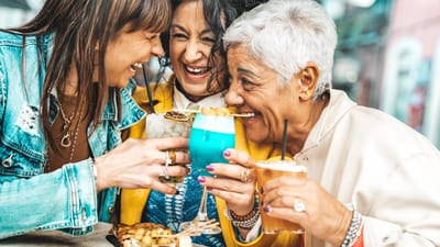 Three women joyfully toasting with colorful drinks