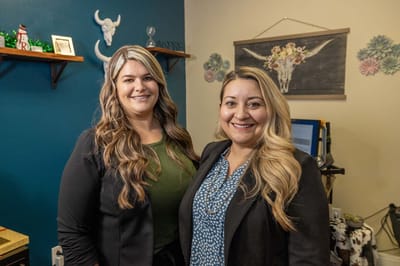 Two staff members smiling in an office setting