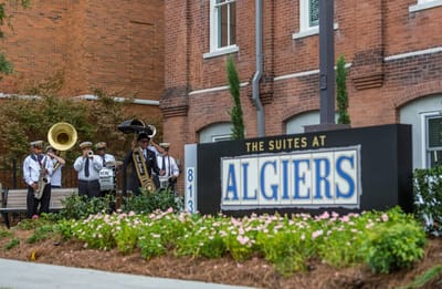 Brass band performing outside Algiers Point facility sign