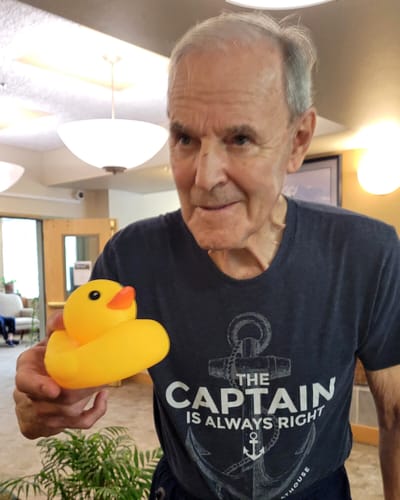 Resident smiling with a rubber duck in a common area