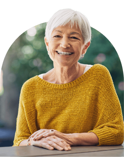 A smiling senior woman in a yellow sweater outdoors