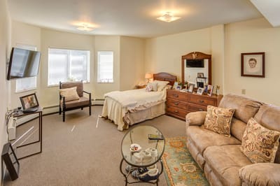 A cozy resident room with a bed and seating area