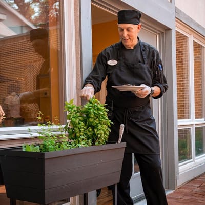A chef serving a meal in an assisted living facility