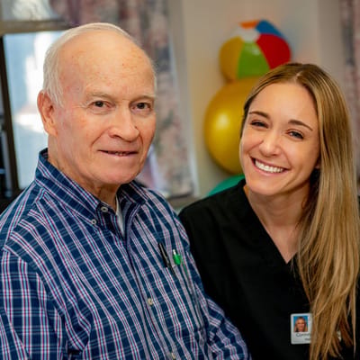 A senior resident smiling with staff member in common area