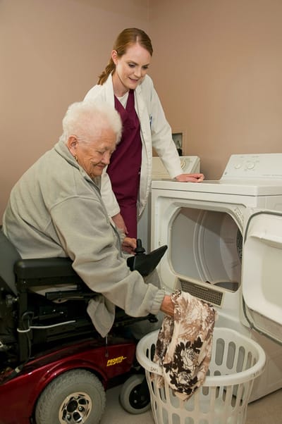 Resident and staff member working together on laundry