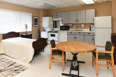 A furnished resident room with kitchen and dining area