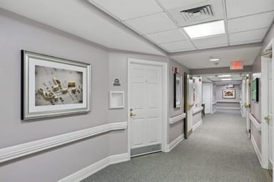 A hallway with framed artwork in an assisted living facility