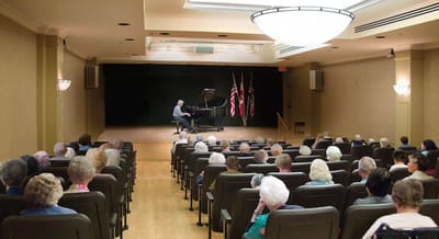 Residents enjoying a live piano performance in a common area