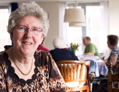 Resident smiling in a common area with others in background