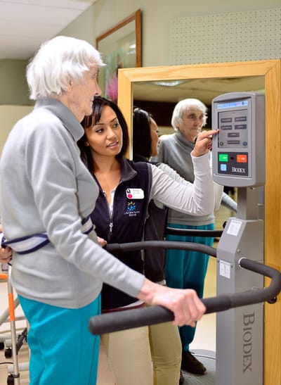 Staff assisting a resident with exercise equipment
