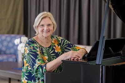 Resident playing piano in a bright activity room