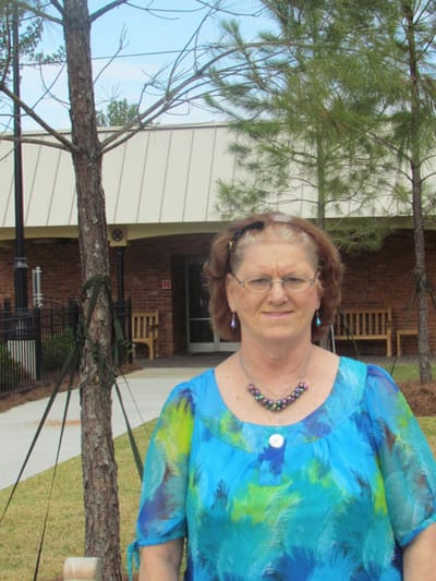 Resident standing outside with a tree in background