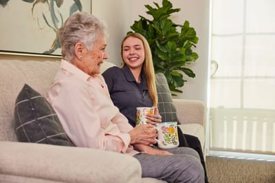 A staff member enjoying tea with a resident in a cozy common area