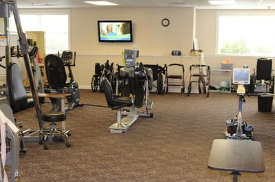 Interior view of a fitness area with equipment and residents' mobility aids