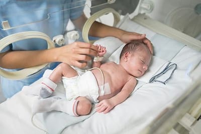 A healthcare professional tending to a newborn in an incubator