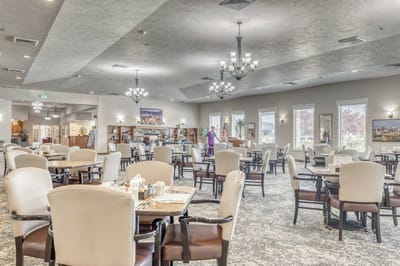 Dining area with tables and residents in a well-lit room