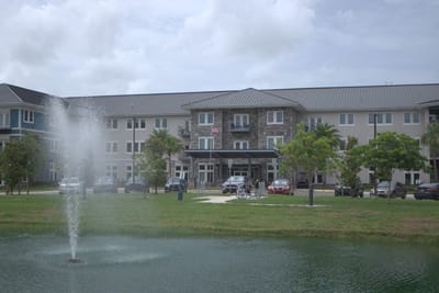 Exterior view of a senior living facility by a pond