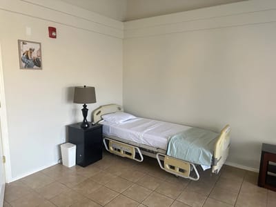 A private resident room with bed and lamp