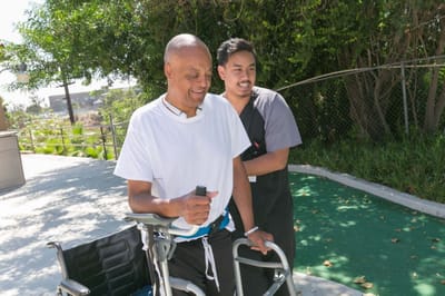 A resident being assisted outdoors by staff member