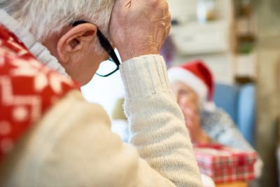 A senior man with glasses and a festive sweater