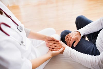 A caregiver holding a senior's hands in a warm interaction