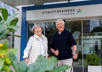 Two residents smiling outside the facility entrance