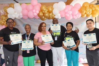 Staff holding certificates in a decorated indoor space