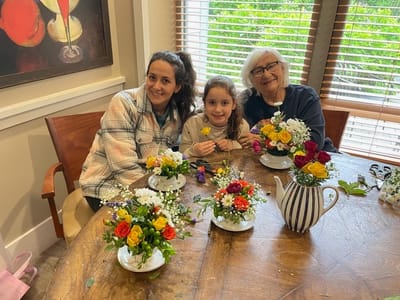 Residents and a child arranging flower bouquets in a bright activity room