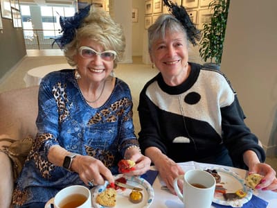 Two women enjoying afternoon tea in a common area