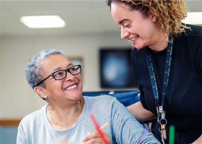 A staff member smiling with a resident inside the facility