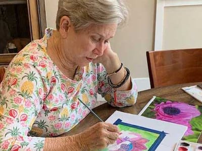 Resident painting at a table in a bright interior