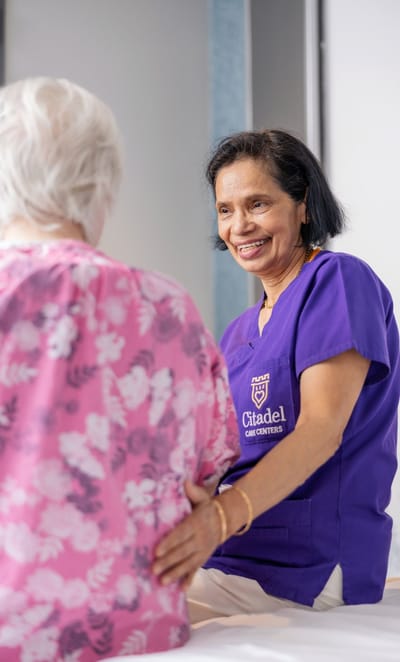 A caregiver smiling while assisting a resident