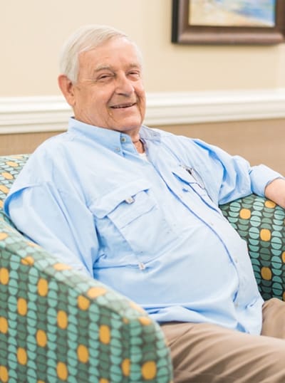 Resident smiling in a cozy chair in the common area