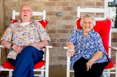 Two residents enjoying chairs on a porch