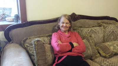 A resident smiling while seated on a couch