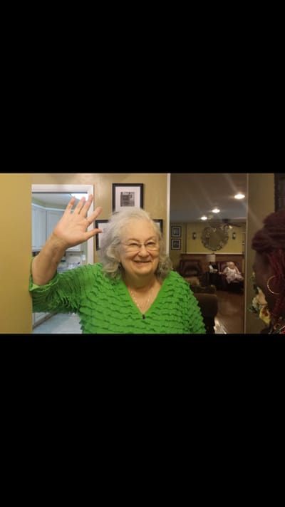 Senior resident waving in a colorful outfit