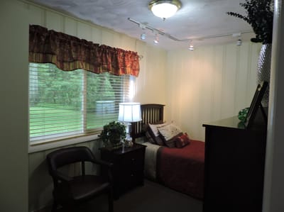 Cozy resident room with bed and chair.